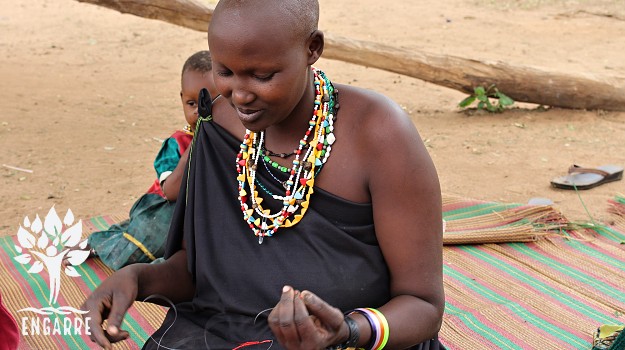 Masajská žena vyrába náhrdelník